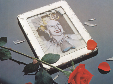 A framed picture of a woman smiling with a rose sitting on top of the smashed frame